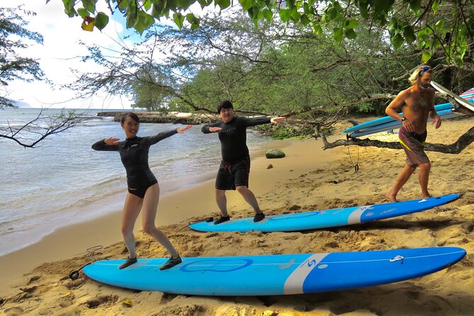 Group Surf Lessons for beginners on the North Shore of Oahu - In the water: catching small waves with guided paddling and standing